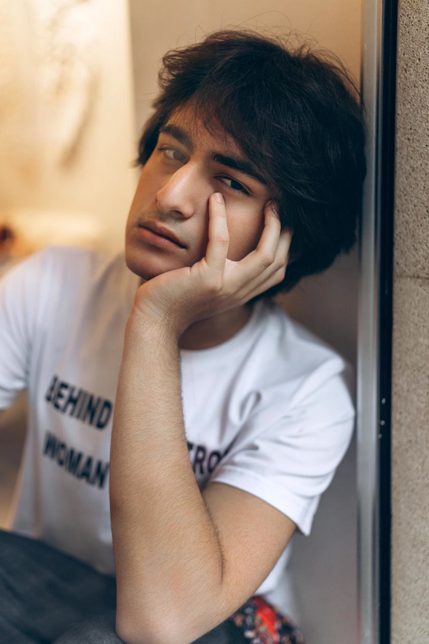 Close-up of Jamal resting his cheek on his hand, in a white slogan T-shirt.